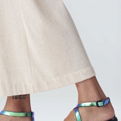 Sandálias rasas iridescentes em pele sintética verde e roxo com calças largas bege