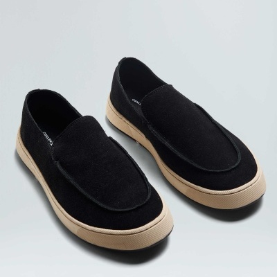 Sapatilhas pretas de tecido com sola bege claro sobre fundo cinzento