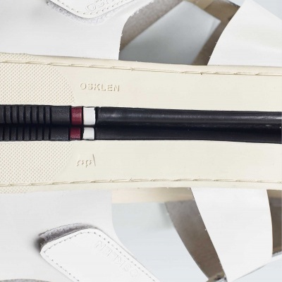 Sandálias brancas de couro com sola bege e detalhe decorativo de bengalas pretas.