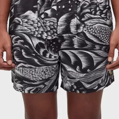 Calções de banho pretos e brancos com padrão abstrato usados por modelo.