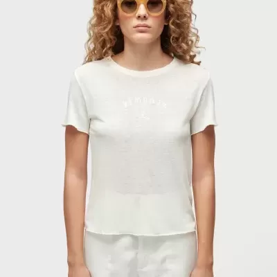 Mulher com t-shirt branca com texto YEMANJA e calções brancos, usando óculos de sol amarelos