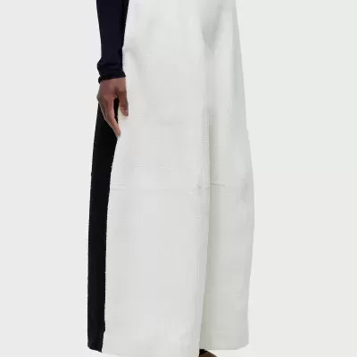 Calças largas brancas com faixa preta lateral e sapatos confortáveis em fundo branco