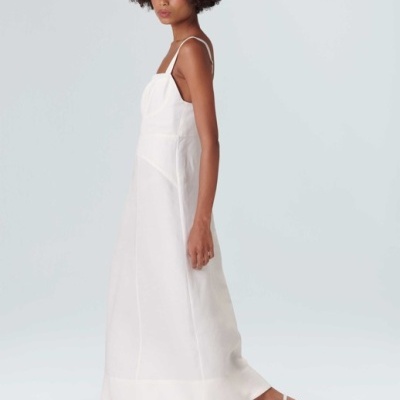 Mulher com vestido branco comprido, chapéu de palha e sandálias brancas em fundo branco