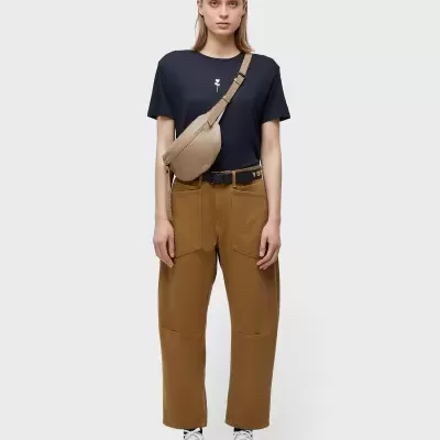 Mulher com roupa casual e bolsa bege sobre fundo branco