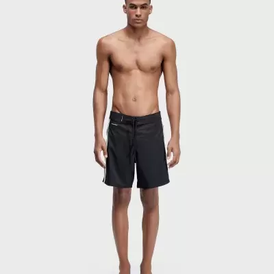 Homem a usar calções de banho pretos com risca branca.