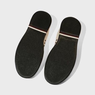 Solado preto texturado de par de sapatos com salto riscado e parte superior bege