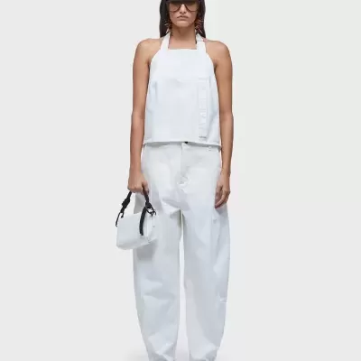 Conjunto branco com top halter e calças largas, bolsa branca com alça preta, sapatos brancos e óculos escuros