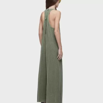 Macacão verde largo com costas expostas, visto de trás, calçada branca