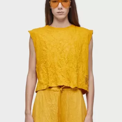 Mulher com conjunto amarelo texturizado e óculos de sol laranja