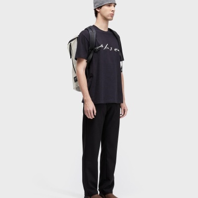 Homem com roupa casual preta, gorro cinzento e mochila bege numa foto de produto