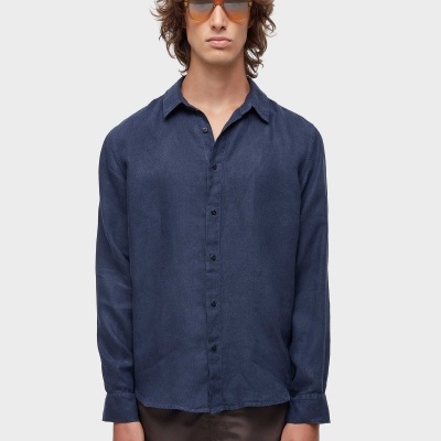 Homem com camisa azul escura, óculos de sol castanhos e calções marrons