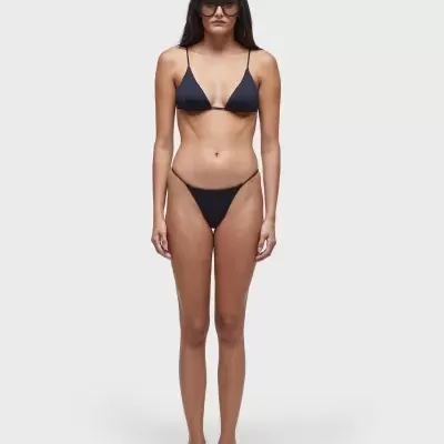 Mulher com fato de banho preto de duas peças e óculos escuros