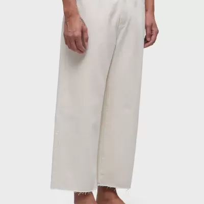 Calças largas brancas com bainha desfiada usadas por pessoa com sandálias pretas