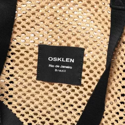 Mala de rede bege e preta com etiqueta OSKLEN
