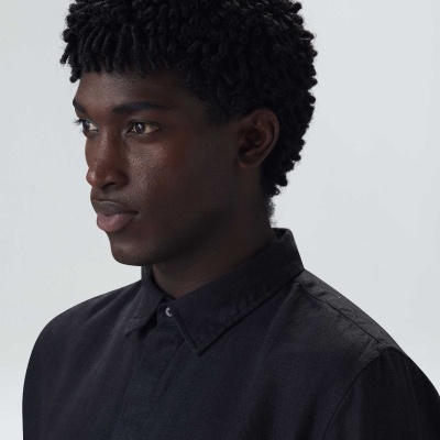 Homem com camisa preta e cabelo frisado curto