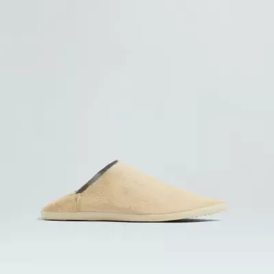 Chinelo bege tipo mule sobre fundo cinzento claro