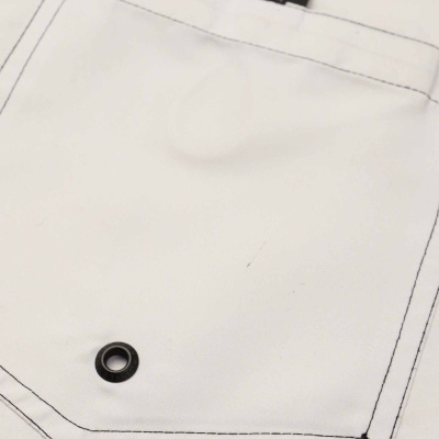 Detalhe de peça de roupa branca com costura preta, ilhó e etiquetas OSKLENSURFING