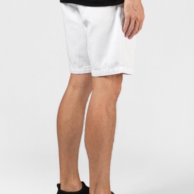 Calções brancos de algodão com dobras na bainha usados por modelo de pé