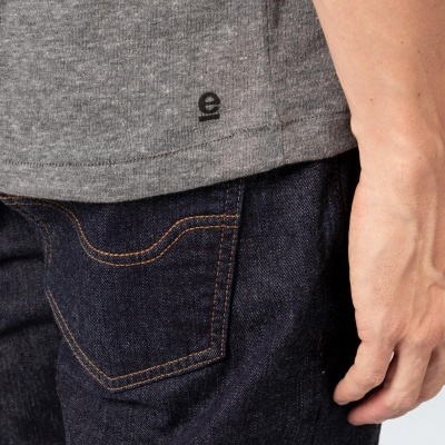 Parte de t-shirt cinzenta e calças de ganga azul escuro com bolso e braço à vista