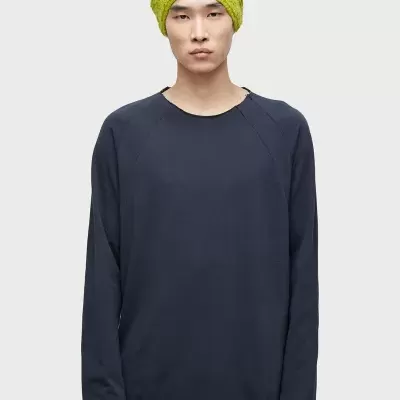 Homem com camisa preta manga comprida e gorro amarelo esverdeado felpudo