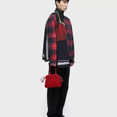 Homem com camisa xadrez vermelha e preta e mala vermelha texturizada