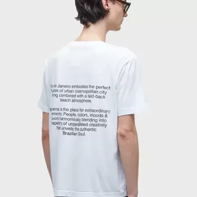 T-shirt branca com texto preto nas costas, usada por modelo de costas, cabelo curto e óculos