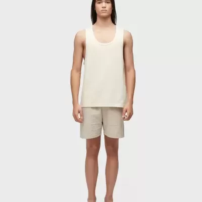 Modelo com regata creme, calções bege e sandálias castanhas