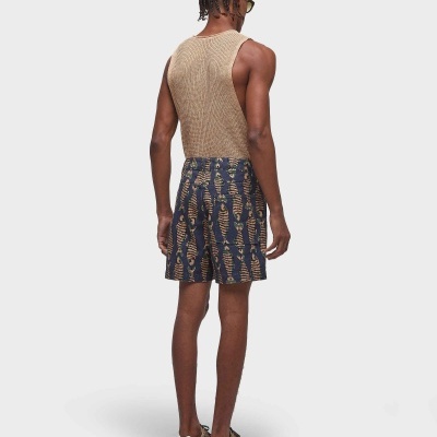 Homem de costas com regata bege e calções azuis com padrão de lobos dourados