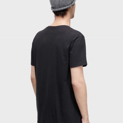 Homem de costas com camisola preta, calças pretas com riscas douradas e gorro cinza