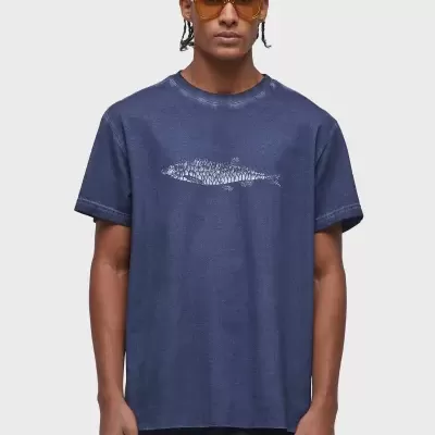 T-shirt azul escura com padrão branco abstrato central e óculos castanhos.