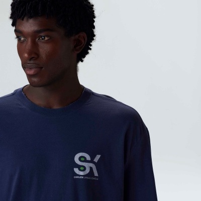 Homem com t-shirt azul-marinho com logotipo 'SX' no peito.