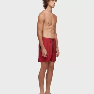 Homem com calções de banho vermelhos e sandálias castanhas