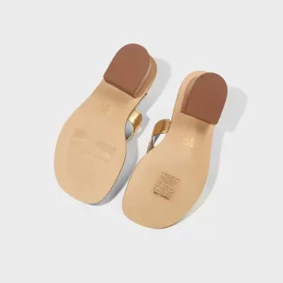 Sandálias douradas femininas vista pela sola com texto OSKLEN