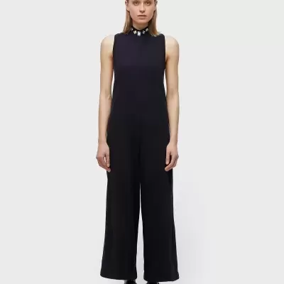 Mulher com macacão preto sem mangas e gola decorada