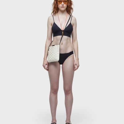 Mulher com biquíni preto e bolsa branca trançada