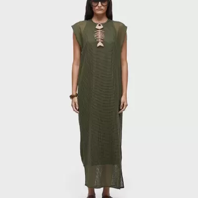 Mulher com vestido verde comprido sem mangas e acessório decorativo