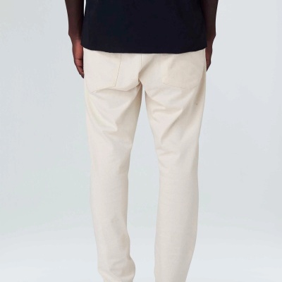 Calças creme vistas de costas com t-shirt e sapatos pretos