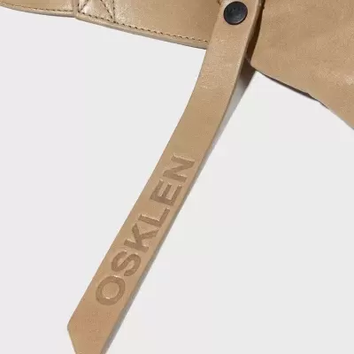 Bolsa de couro bege com tira gravada com texto OSKLEN