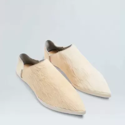 Sapatos tipo mocassins bege com textura peluda e bico fino.