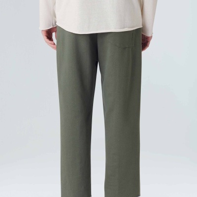 Calças verdes-oliva retas com sapatos bege e camisola branca de costas