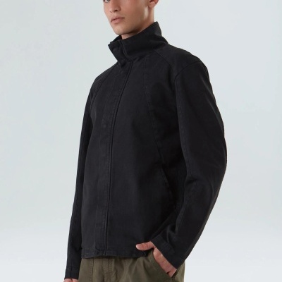 Homem com jaqueta preta e calças verde-oliva em fundo branco