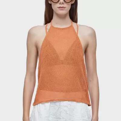 Top feminino de malha laranja com calças brancas e óculos de sol