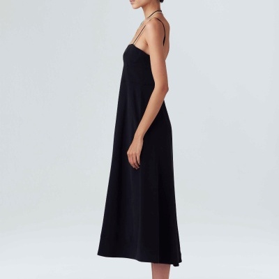 Mulher em vestido preto longo de alças e sandálias pretas de perfil