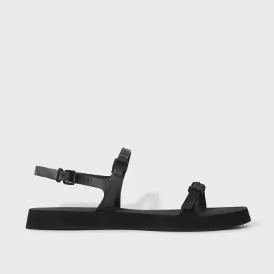 Sandália preta com tiras e fivelas em fundo branco.