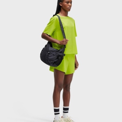 Mulher com roupa verde-limão, mochila preta OAKLYN, meias brancas com riscas pretas e sapatos creme
