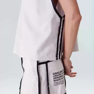 Conjunto de roupa branca com detalhes em preto, peça superior sem mangas e saia ou calça com bolso lateral e texto impresso.