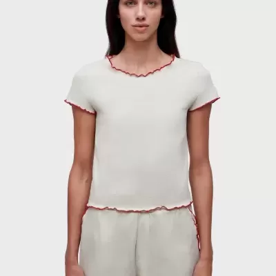 Conjunto bege com t-shirt e calções de bainhas vermelhas, modelo feminino de frente