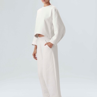 Mulher com conjunto branco e tênis laranja e preto em fundo branco