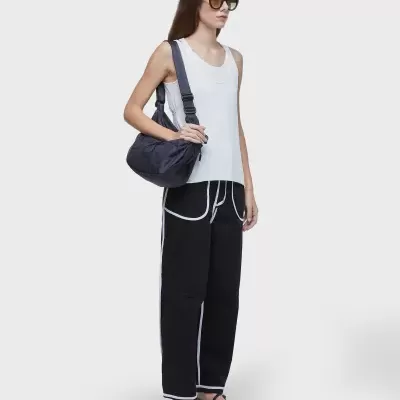 Mulher com roupa casual e mala preta sobre o ombro