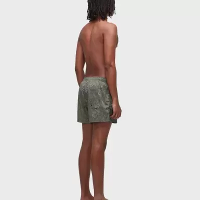 Pessoa de costas com calções de banho cinza com padrão geométrico e chinelos castanhos